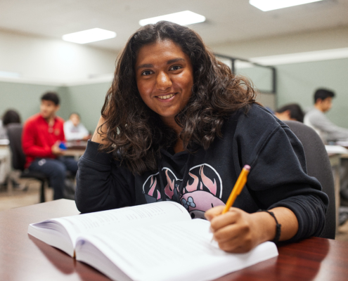 A high school student studying at a desk to raise her GPA.