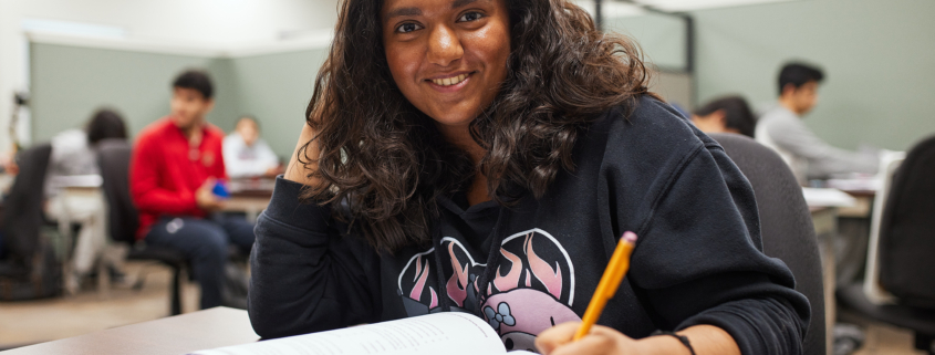 A high school student studying at a desk to raise her GPA.